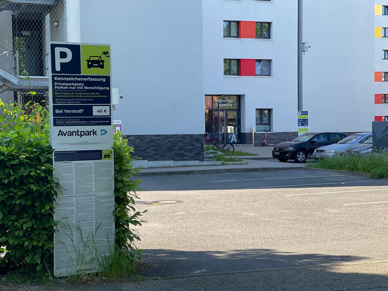 Das Foto zeigt ein Schild vom Anbieter Avantpark, im Hintergrund sieht man den Eingang der Wohnanlage Gescherweg 72.